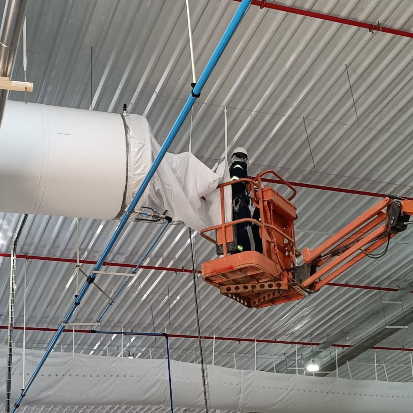 Técnico da Higidutos higienizando duto industrial em plataforma elevatória
